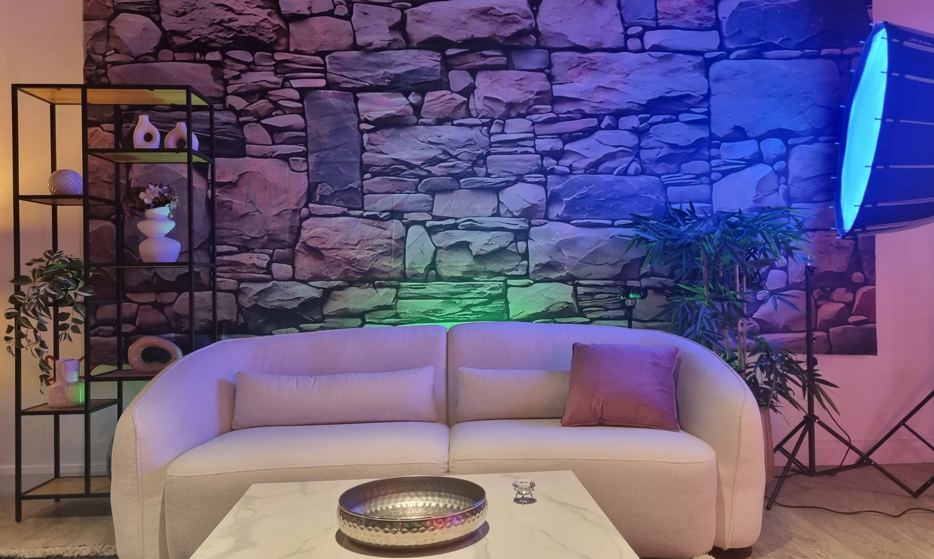 Cream bouclé sofa against the RGB-washed stone wall