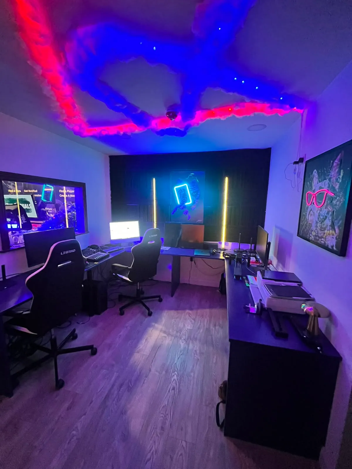 The production room: edit desks, monitors and neon art under the red and blue cloud ceiling