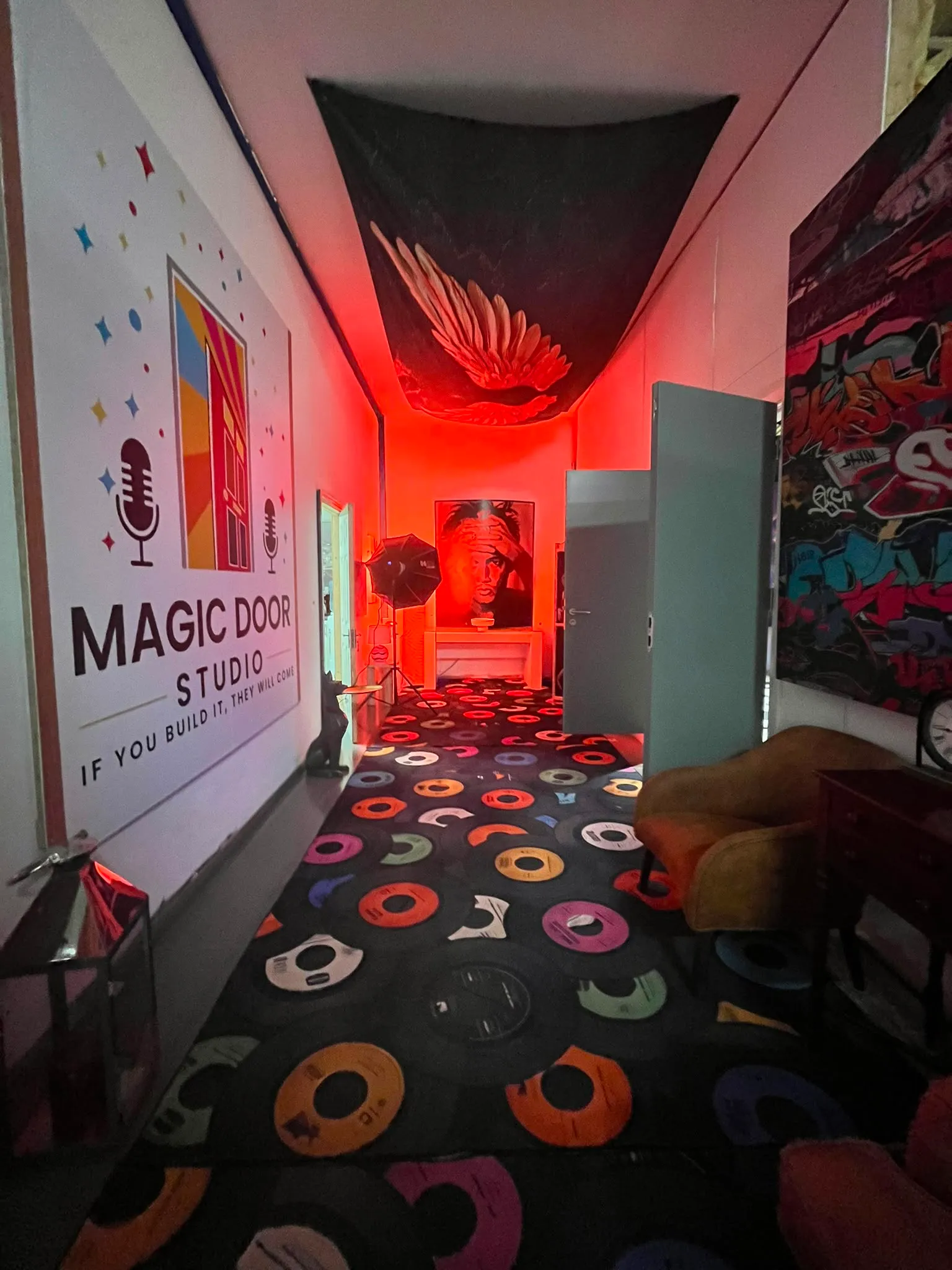 The entrance hall: logo wall, vinyl-record carpet and the red-lit angel wing