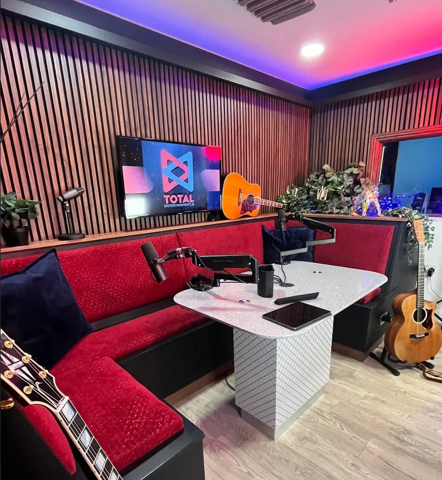 Studio 1 dressed for Total Entertainment: neon logo, guitars and the scarlet booth under the walnut slats