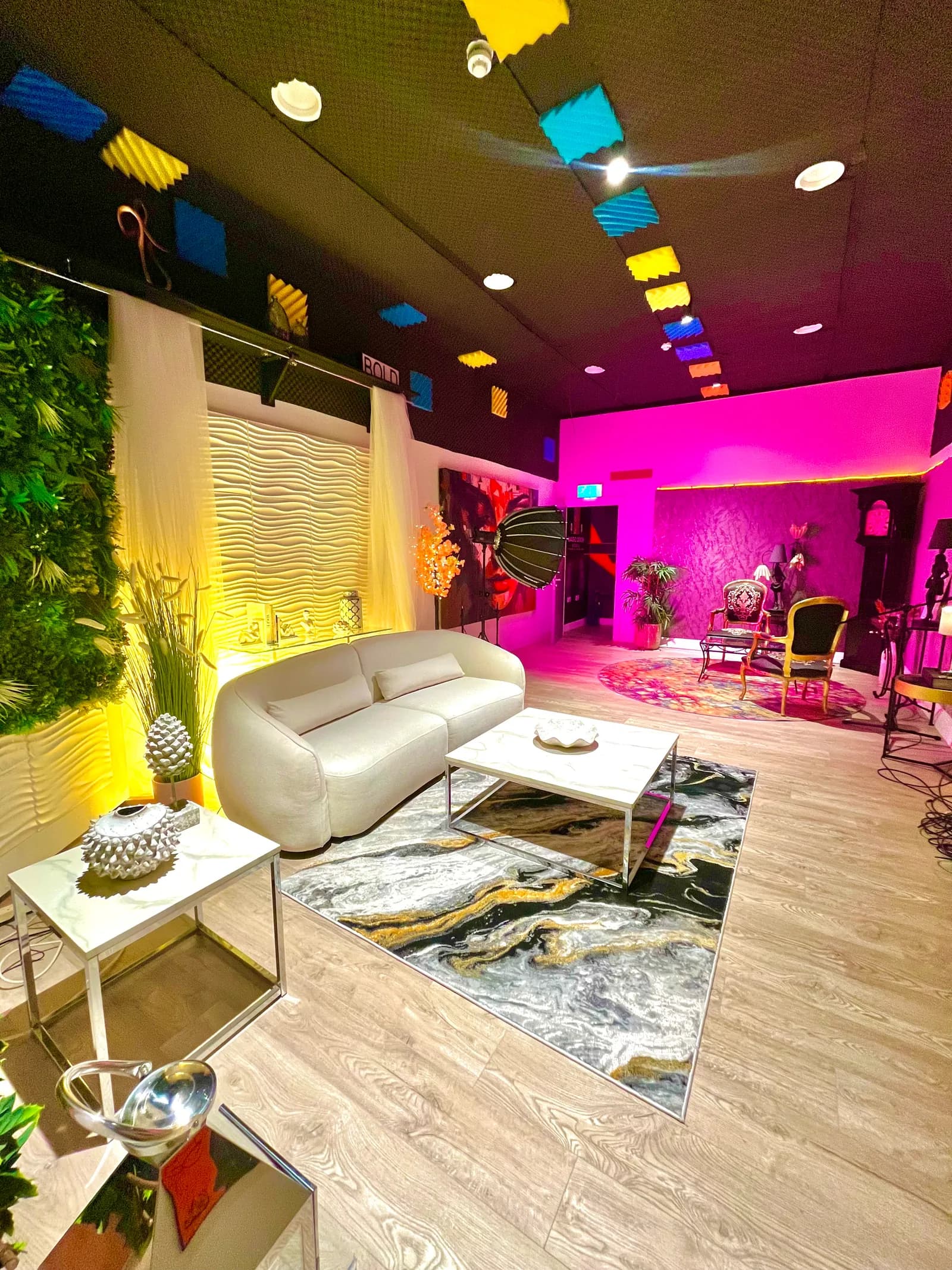 Studio 2's full floor: the yellow-lit wave wall lounge, marble rug and the pink parlour glowing at the back